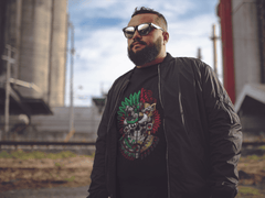 Hombre usando playera con diseño prehispánico dividido con máscara jaguar y elementos aztecas modernos